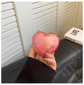 Detail view of pink heart-shaped bag with geometric facets and golden chain