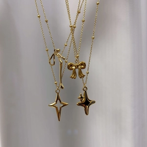 Gold stainless steel beaded necklaces featuring star and butterfly pendants on white fabric
