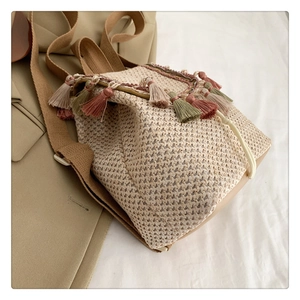 Detailed close-up of straw backpack featuring colorful tassels and cotton drawstring straps