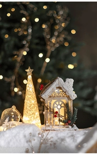 Close-up of lighted wooden Christmas house and tree decoration with warm LED glow