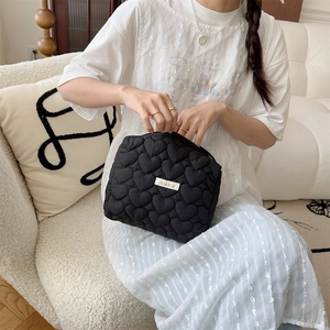 Detailed shot of a black quilted makeup bag featuring an elegant heart stitch pattern