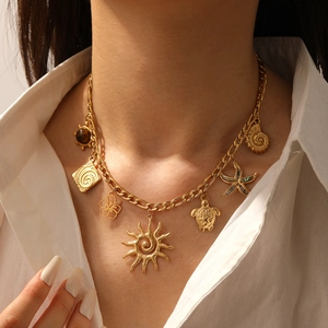 Close-up of gold layered necklace with tiger eye stone and various ocean themed charms
