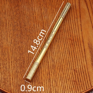 Detailed macro of golden brass bamboo pen showing engraved Chinese characters on wood