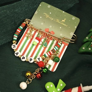 Détail de la broche de Noël avec glands, cloches et perles HAPPY sur carte festive