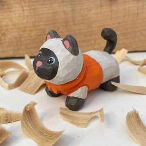 Détail de figurine chat siamois en bois sculpté avec texture et petit pull orange