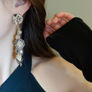Gros plan de boucles d'oreilles pendantes argentées à texture lave sur mannequin