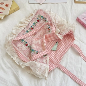 Detail of floral embroidery and lace trim on pink checkered canvas tote bag