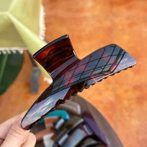 Macro shot of large butterfly hair claw clip with tortoise shell pattern in hand