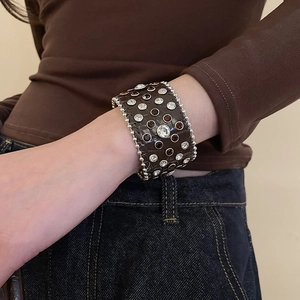 Vue macro d'un large bracelet en cuir de crocodile marron avec cristaux et clous argentés