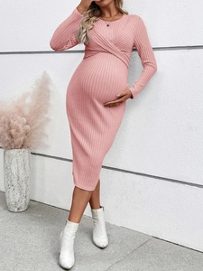 Detail of pink knitted maternity dress featuring a twist knot front and long sleeves