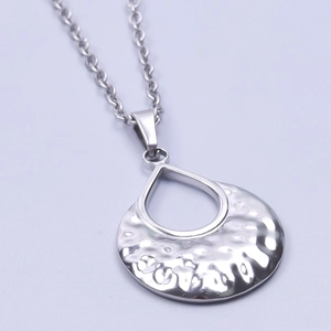 Macro detail of a silver stainless steel necklace with a hammered round pendant texture