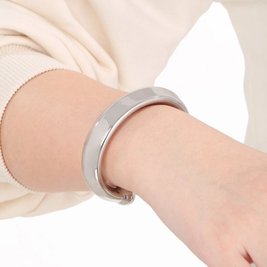 Gros plan sur un bracelet manchette argenté en forme de C porté au poignet d'un mannequin