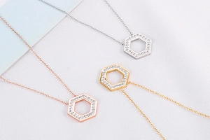 Detail of three hexagonal geometric necklaces in silver, gold, and rose gold with pavé crystals