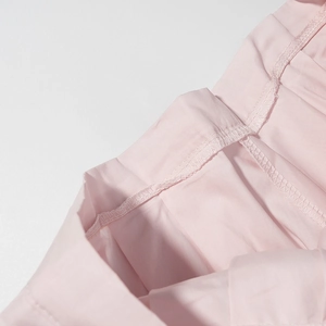 Gros plan sur les détails de couture et la texture du tissu lisse de cet ensemble rose