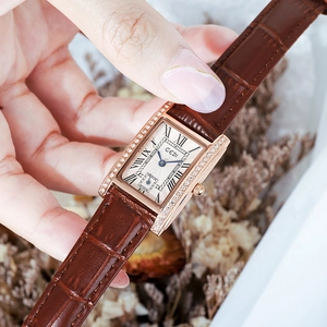 Elegant gold square watch with brown leather strap and roman numeral dial on a wrist