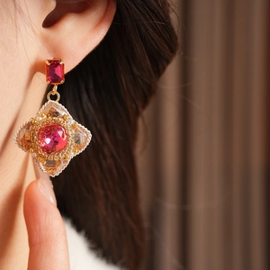 Macro detail of vintage court-style earrings with red gemstones and gold beads
