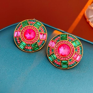 Dettaglio di orecchini vintage dorati con strass colorati su una scatola blu