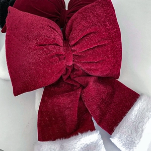 Macro detail of red velvet Christmas bow with silver glitter and white faux fur trim