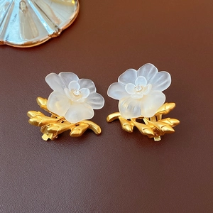 Macro detail of vintage gold flower earrings with white petals and rhinestones on leather