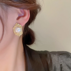 Detail of vintage flower pearl earring with gold wavy metal base on model