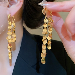 Détail macro de boucles d'oreilles à pampilles dorées avec sequins ronds superposés