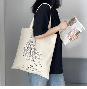 Detailed view of cat graffiti print on cream canvas tote bag with artist text