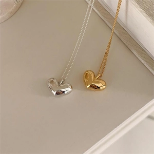 Detailed macro view of 3D polished heart pendants in gold and silver finishes