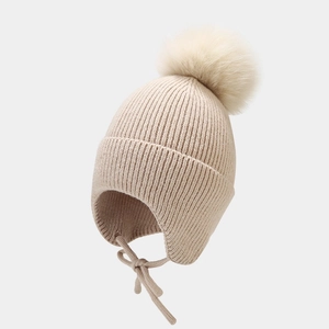 Détail du bonnet en tricot à oreillettes avec grand pompon et liens tissés
