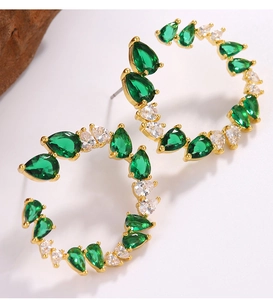Detail of C-shaped gold earrings with emerald green and white pear-cut zircon crystals