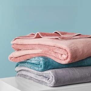 Close-up of high-density flannel blankets in pink, blue, and grey showing soft texture