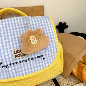 Detail einer karierten gesteppten Kindertasche mit süßem Capybara-Plüschtier-Anhänger