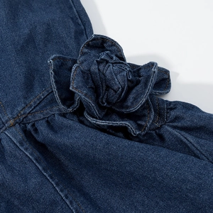 Détail de la fleur en denim 3D et des coutures sur une robe bleu foncé