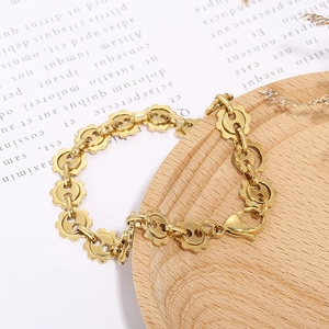 Golden bracelet with petal shaped hollow links and lobster clasp on a wooden tray