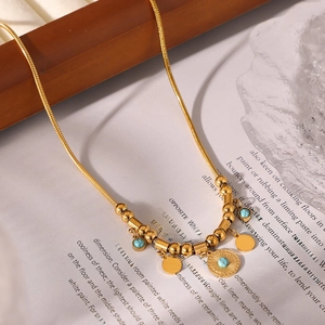 Golden turquoise sunburst pendant necklace with snake chain displayed on book pages