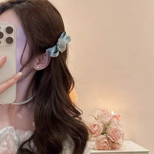 Elegant light blue mesh bow hair clip with pearl and rose detail worn by a model