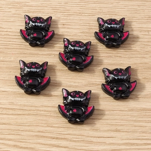 Close-up of cute black and pink resin cartoon bat charms for DIY phone case craft decoration