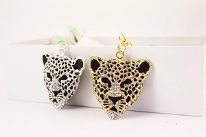 Detailed view of gold and silver leopard head pendants with sparkling rhinestones