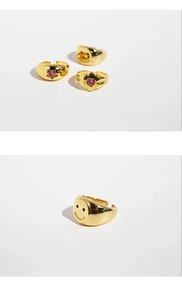 Detailed view of adjustable gold rings with pink zircon stars and smiling face designs