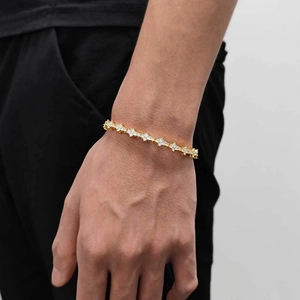 Macro shot of gold-plated tennis bracelet with white zircon cross star charms on wrist