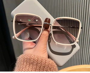 Détail de la charnière métallique et de la monture carrée beige des lunettes de soleil