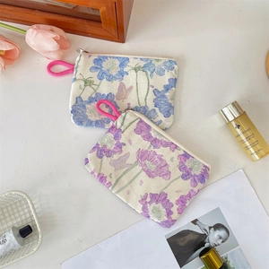 Detail of floral canvas pouches with zipper closures and pink woven rope handles