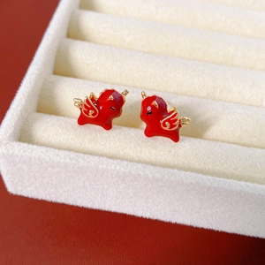 Close-up of 18k gold plated red dragon stud earrings on a beige velvet jewelry box