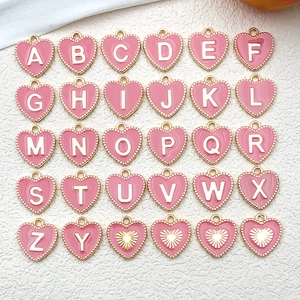 Detail shot of heart-shaped pink enamel letter charms with gold-plated metal alloy edges