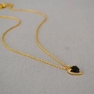 Macro detail of heart pendant with faceted black stone and micro-pave cubic zirconia