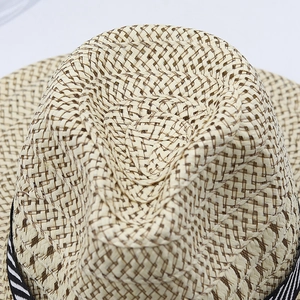 Close-up of woven straw fedora crown with black and white striped ribbon detail
