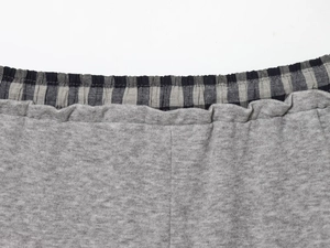 Close-up of the elastic waistband with black and grey plaid patchwork on grey knit pants