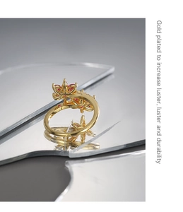 Detail of gold plated ring with red zircon flower on a reflective mirror surface