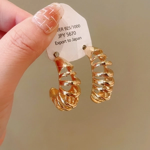 Detail showing gold spiral geometric earrings held on 925 silver needle display card