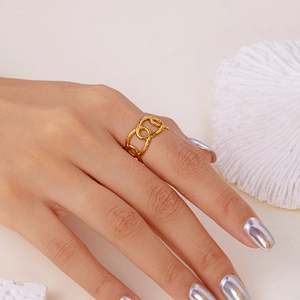 Detail of interlocking gold rings with textured surface shown on model with coral decor