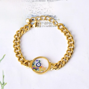Gold chain bracelet featuring a transparent round charm with evil eye and star crystals